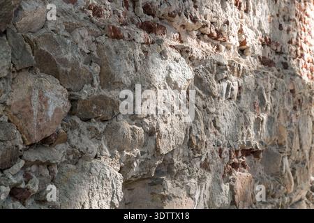 Detaillierter Hintergrund einer Stein- und Ziegeloberfläche, die durch die Zeit im Sonnenlicht abgenutzt wurde Stockfoto