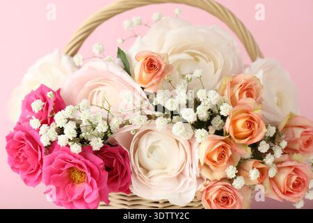 Schöne Blumen im Korb auf rosa Hintergrund, Nahaufnahme Stockfoto