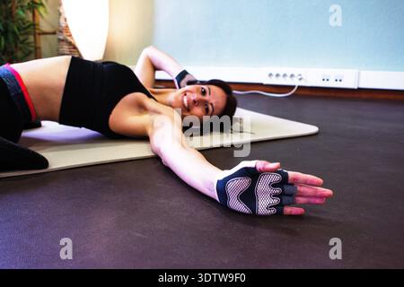 Frau, die auf Yogamatte trainiert, lächelt während des Indoor-Trainings Stockfoto