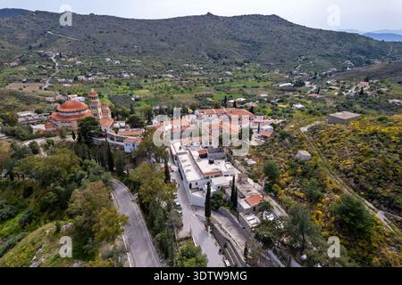 Blick aus der Vogelperspektive auf das Kloster Agios Nektarios in Ägina, Griechenland, umgeben von grünen Hügeln und ländlicher Landschaft, mit der roten Kuppelkirche Stockfoto
