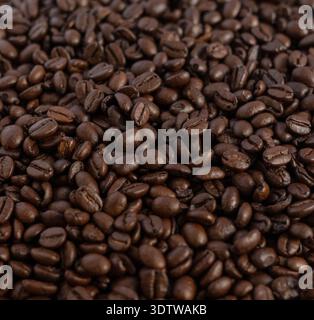 Eine detaillierte Vollformataufnahme dunkel gerösteter Kaffeebohnen mit kräftiger brauner Textur, perfekt für den Einsatz als kulinarischer Hintergrund oder in der Lebensmittelindustrie Stockfoto