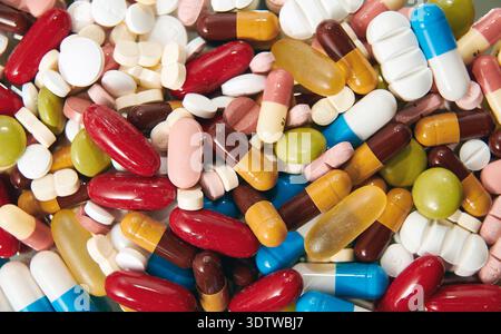 Eine Nahaufnahme aus dem Hochwinkel bietet eine detaillierte Ansicht einer großen, durcheinander geworfenen Sammlung verschiedener pharmazeutischer Pillen und Kapseln. Die Medikamente sind Stockfoto