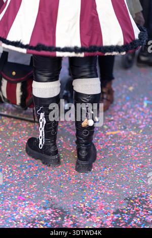 Karnevalskostüme Stiefel gehen auf der Konfetti-bedeckten Straße während des Fasnacht Festivals in Luzern, Schweiz. Festliche Parade. Stockfoto