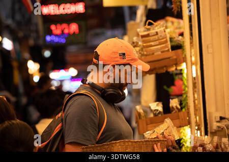 BANGKOK, THAILAND, 28. JAN 2026: Mann, der Produkte auf dem lokalen Markt wählt, Seitenprofil, auf dem Chatuchak Markt. Stockfoto