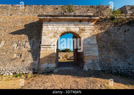 Das steinerne Eingangstor zur Burg von Pylos in Griechenland zeigt die bogenförmige Öffnung, die strukturierten Wände und den sonnendurchfluteten Innenhof dahinter. Stockfoto