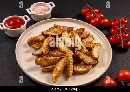 Teller mit frisch gebackenen Kartoffelscheiben, serviert einen herzhaften Snack oder eine Vorspeise, ergänzt durch kleine Schüsseln Ketchup und rosafarbenes Salz, mit Bündeln davon Stockfoto