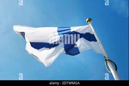 Die finnische Nationalflagge winkt auf Einem Pole gegen den Himmel Stockfoto