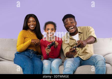 Die Familie spielt gern gemeinsam Videospiele auf einer Couch in gemütlicher Wohnzimmeratmosphäre Stockfoto