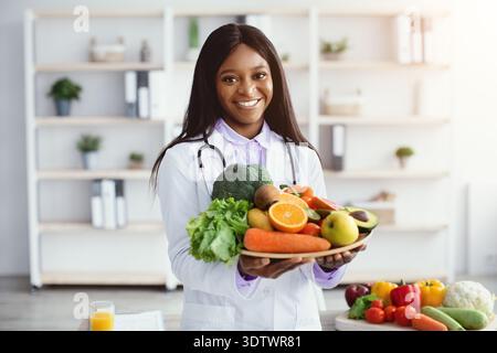Doctor hält frisches Obst und Gemüse in einer modernen Küchenumgebung für gesunde Ernährung Tipps Stockfoto