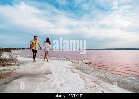 Ein idyllisches Paar genießt einen friedlichen Spaziergang entlang des pulsierenden Ufers des Rosa Sees in Torrevieja, Spanien, umgeben von einer atemberaubenden Landschaft darunter Stockfoto