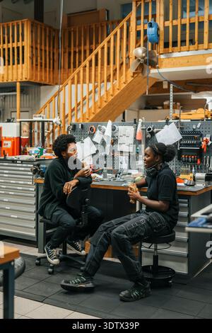 Männliche und weibliche Arbeiter essen Wrap-Sandwich während der Pause in der Fabrik Stockfoto