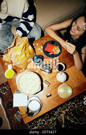 Hochwinkelansicht von Mann und Frau, die Junk Food essen, während sie zu Hause sitzen Stockfoto
