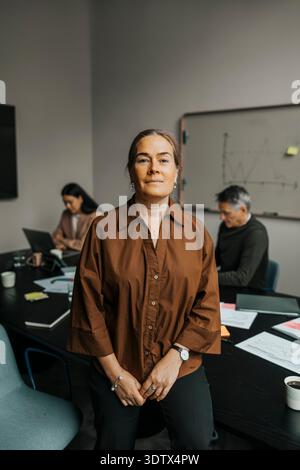 Porträt einer selbstbewussten Geschäftsfrau, die in der Nähe des Tisches im Besprechungsraum posiert Stockfoto
