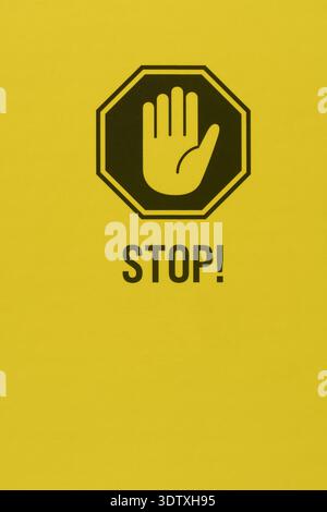 Schwarz bedrucktes Stoppschild mit Handsymbol auf gelber Kartonstruktur, flache Oberfläche des Verpackungsmaterials mit Text, Nahaufnahme mit Kopierraum Stockfoto