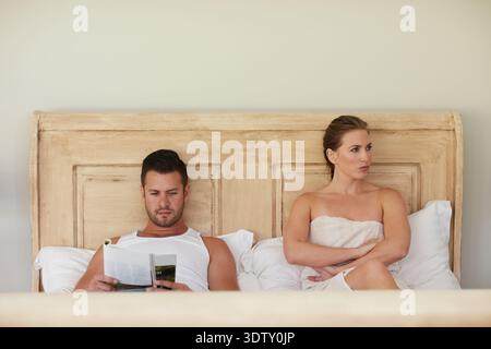 Frustration, Ignorieren und lesen mit einem Paar zusammen im Bett für Streit, Konflikt oder Schweigen. Verärgert, buchen oder kämpfen mit Mann und Frau im Schlafzimmer Stockfoto