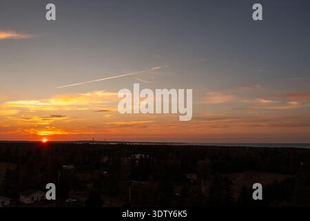 Drohnenfoto von einem pulsierenden Sonnenuntergang über den Feldern und Bäumen von Prince Edward Island in Kanada mit goldenem Licht, das über das darunter liegende Ackerland leuchtet Stockfoto