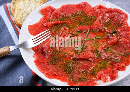 Rindfleisch-Carpaccio in Olivenöl und Kräutern mariniert, eine italienische Gourmet-Vorspeise Stockfoto