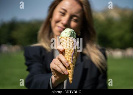 Fröhliche positive Frau posiert mit Eis in der Hand und genießt erfrischende Leckereien am Sommertag. Stockfoto