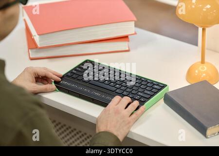 Mann mittleren Alters mit Braille-Tastatur während des Studiums in der Bibliothek Stockfoto
