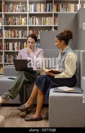 Junger Mann und Frau, die zusammen in Bibliothekseinrichtungen studieren Stockfoto