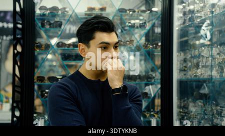Aufmerksamer Mann, der stilvolle Brillen in einer modernen Optik-Boutique wählt Stockfoto