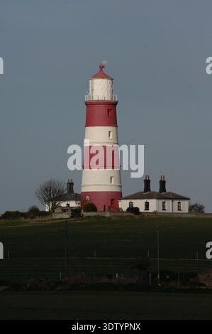 Der Happisburgh Lighthouse an der Nordküste von Norfolk. Der 1791 erbaute Leuchtturm ist die älteste Arbeitsleuchte in East Anglia und der einzige unabhängig betriebene Leuchtturm in Großbritannien, der seit 1990 vom Happisburgh Lighthouse Trust verwaltet wird. Die ikonischen roten und weißen Bänder dienen als wichtiges maritimes Markierungsfeld. Der Ort ist ein Schwerpunkt für die Untersuchung der Küstenerosion, da die sich zurückziehenden Klippen der Cromer Ridge das Dorf und seine historischen Strukturen erheblich bedrohen. Dieser Turm aus dem 18. Jahrhundert ist ein Symbol sowohl für die maritime Geschichte als auch für die ökologischen Herausforderungen, denen die britische Küste gegenübersteht. Stockfoto