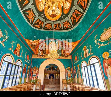 Das Innere der St. John the Baptist Church zeigt farbenfrohe Gemälde und einen zentralen Kronleuchter. Besucher genießen die Kunst und Architektur im Inneren. Stockfoto