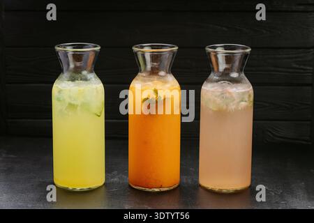 Drei frische hausgemachte Limonaden mit Eis und Minze in Glasflaschen auf dunklem Hintergrund Stockfoto