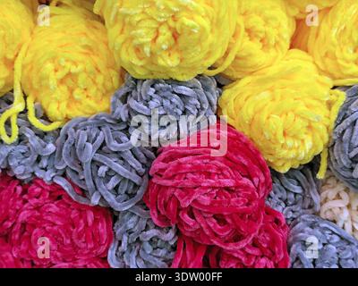 Bunte Knäuel aus weichem Chenille-Garn in Gelb-, Grau- und Rottönen, Nahtstruktur für Strick- und Bastelhintergründe Stockfoto