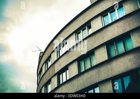 Eine abstrakte, flache architektonische Aufnahme eines großen, geschwungenen modernistischen oder brutalistischen Gebäudes. Das rhythmische Muster der Fenster erzeugt ein kraftvolles V Stockfoto