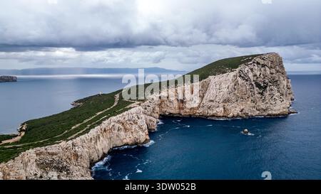 Spektakuläre Hochwinkelansicht der Landzunge Capo Caccia in Alghero. Das Bild fängt die imposanten weißen Kalksteinklippen ein, die in das tiefe Blau stürzen Stockfoto