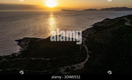 Atemberaubendes Panorama-Drohnenbild, das den goldenen Sonnenuntergang über der Landzunge Capo Malfatano einfängt. Das Foto zeigt die Küstenstraße, die sich durchwindet Stockfoto