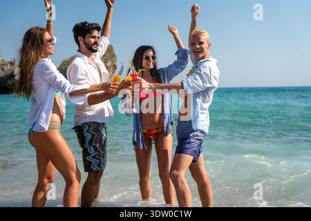 Gruppe von jungen Freunden, die Spaß am Strand mit bunten Getränken haben und im Sommer in der Sonne lachen Stockfoto