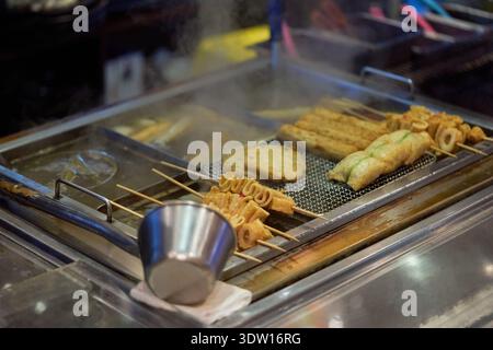 Street-Food-Szene in Seomyeon, Busan, Südkorea, mit dampfendem tteokbokki, Fischkuchen, und herzhafte Pfannkuchen auf einem traditionellen Markt im Freien Stockfoto
