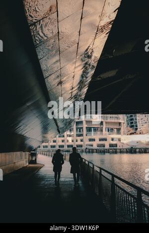 Die Leute laufen neben dem Fluss unter der Brücke in Chicago. Stockfoto