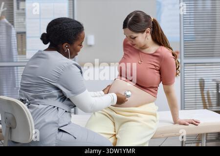 Kaukasische schwangere junge Frau untersucht von schwarzem Frauenarzt in der Klinik Stockfoto
