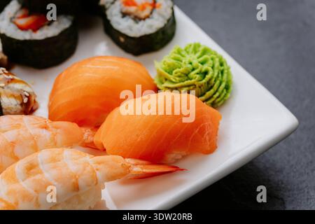 Sushi-Set mit Lachsgarnelen-Nigiri und Brötchen auf weißem Teller Stockfoto