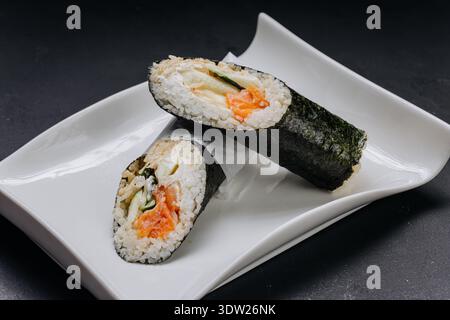 Temaki-Sushi-Handrolle mit Lachsgurke und Frischkäse auf weißer Platte Stockfoto