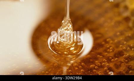 Honig tropft aus Waben extrem Makro. Natürliche Bienen Wachszellen, Goldnektar. Pures goldenes Elixier. Erstaunlich leckerer Fluss. Gelber Hintergrund. Hoch qua Stockfoto
