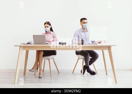 Büromitarbeiter arbeiten während der Arbeitszeit in Modern Workspace mit Masken zusammen Stockfoto