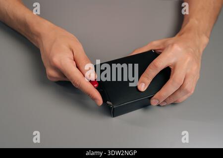 Menschliche Hände öffnen neue elektronische Gadget-Box mit einem kleinen roten Messer, bereiten sich auf die Produktenthüllung vor, konzentrieren sich auf das Auspacken, Nahaufnahme Stockfoto