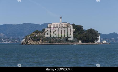Ein detaillierter Blick auf die Insel Alcatraz, umgeben von glitzerndem Wasser. Das Bild fängt die historische Präsenz der Insel und ihre markante Lage ein. Stockfoto