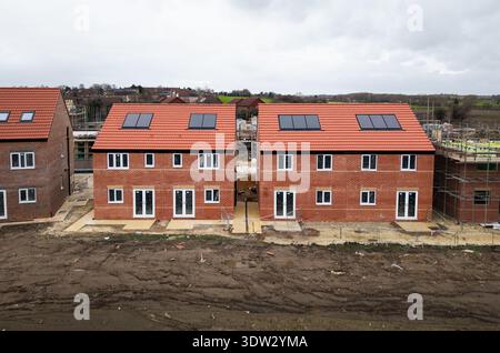 Blick aus der Vogelperspektive über erschwingliche Doppelhaushälften mit umweltfreundlichen Heizungssystemen einschließlich Dachsolarpaneelen auf einer Baustelle in der Stockfoto