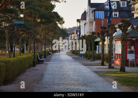 Ruhige Strandpromenade in Binz am frühen Morgen: Historische Resortarchitektur, gepflegte Gassen und Bänke im sanften Licht auf Rügen Stockfoto