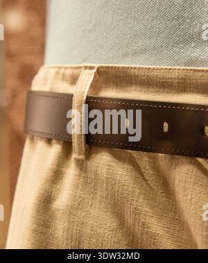 Nahaufnahme eines raffinierten Outfits mit beigefarbener Hose mit Gürtelschlaufe und braunem Ledergürtel Stockfoto