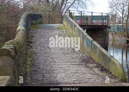 Steinbrücke mit Kopfsteinpflaster über den Ashton Canal, Tameside, Großbritannien. Stockfoto