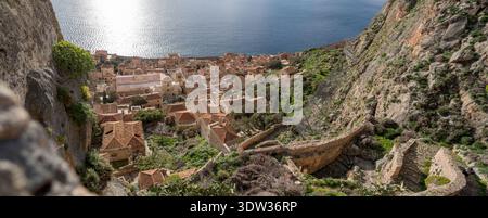 Panoramablick von den oberen Befestigungsanlagen von Monemvasia, Griechenland, mit Blick auf die untere Stadt mit lebendiger grüner Frühlingsvegetation. Stockfoto