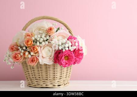 Schöne Blumen im Korb auf weißem Holztisch. Leerzeichen für Text Stockfoto