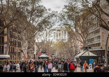 BARCELONA, SPANIEN - 5. APRIL 2025: Fußgängermassen spazieren entlang der Ramblas in Barcelona, Spanien, auf einem von Bäumen gesäumten Boulevard mit Kiosken, Geschäften und c Stockfoto