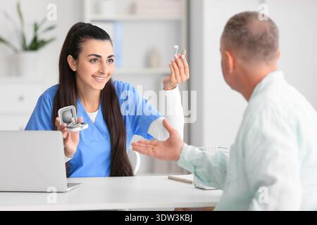 Ärztin zeigt Hörgerät in der Klinik Stockfoto